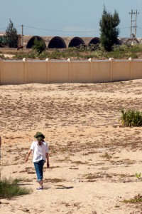 Donut Dollie Dorset (Hoogland) Anderson walking near the perimeter wall and in sight of the Vietnam War era quonset hut aircraft hangars of what was the Tuy Hoa Air Base, which was home of the 31st Tactical Fighter Wing from 1966-70