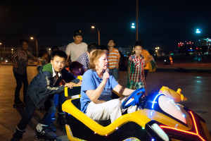 Donut Dollie Mary (Blanchard) Bowe behind the wheel of a bumper car, and being helped by the local children, at the oceanside bumper car park in Tuy Hoa, Vietnam