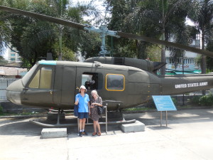 Red Cross Donut Dollies Dorset (Hoogland) Anderson and Mary (Blanchard) Bowe standing in front of a Bell UH-1 Huey Helicopter at the War Remnants Museum in Ho Chi Min City, Vietnam