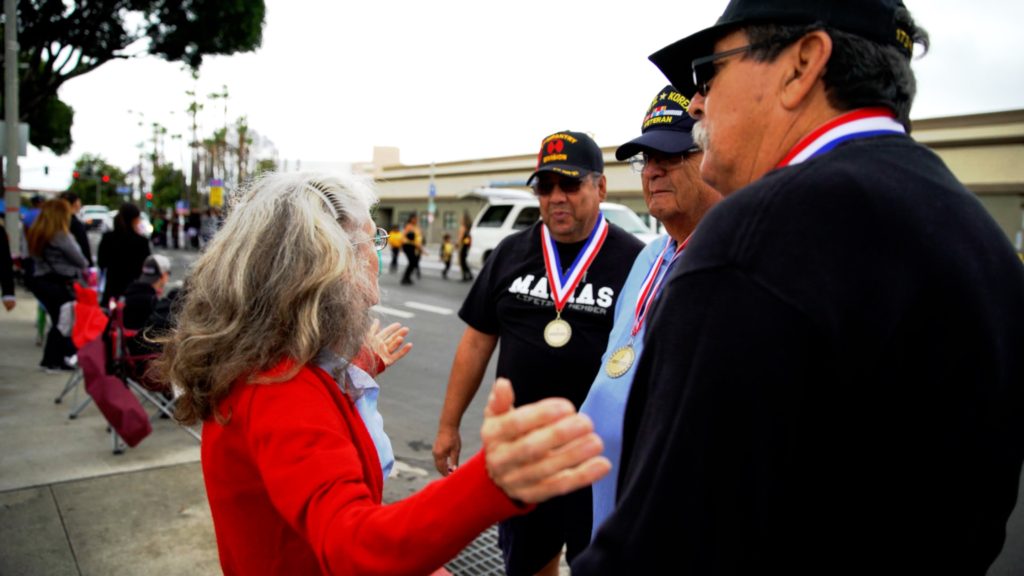 Donut Dollie Dorset Hoogland Anderson thanking Korean Veteran Danny Macias (left), WWII & Korean Veteran Moses Diaz (center) and Veteran David Diaz Gonzales (right) for their service at the Salute to Veterans Parade in Riverside, CA