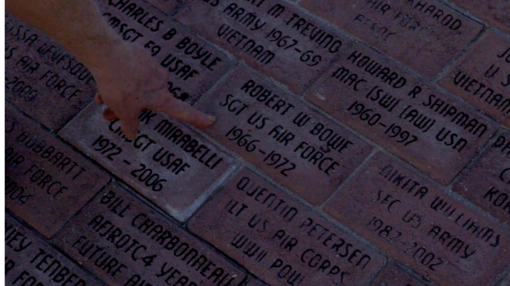 Donut Dollie Mary Blanchard Bowe pointing to the brick honoring her husband Robert Bowe at the Veterans Memorial Plaza in Schertz, TX